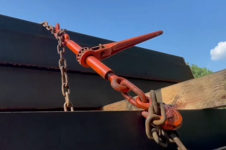 Ratchet binder tensioning a chain over a load