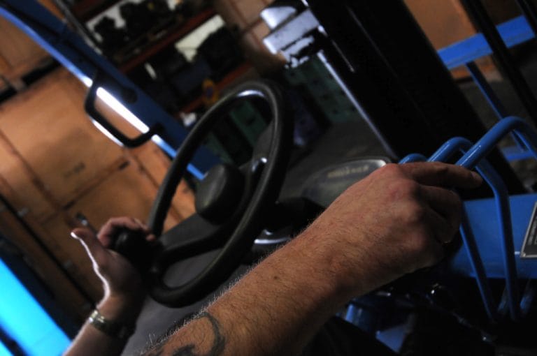 Operator's hands on a steering wheel and hydraulic levers