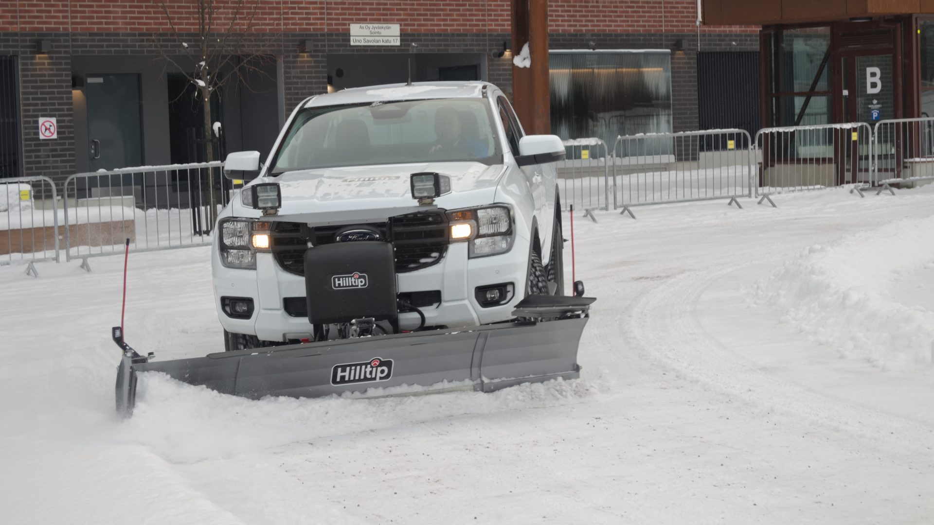 Pickup truck with a front-mounted plow clearing a snowy lot