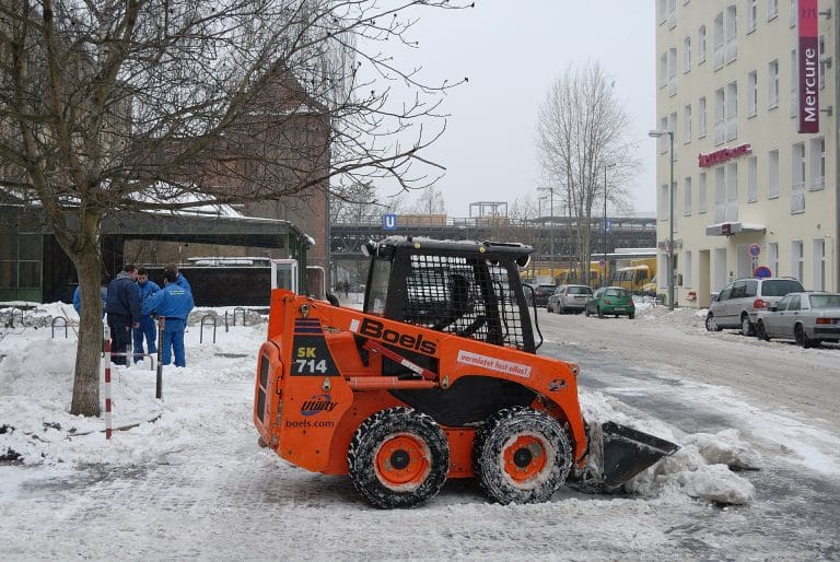 Skid-steer loader clearing snow on a city street