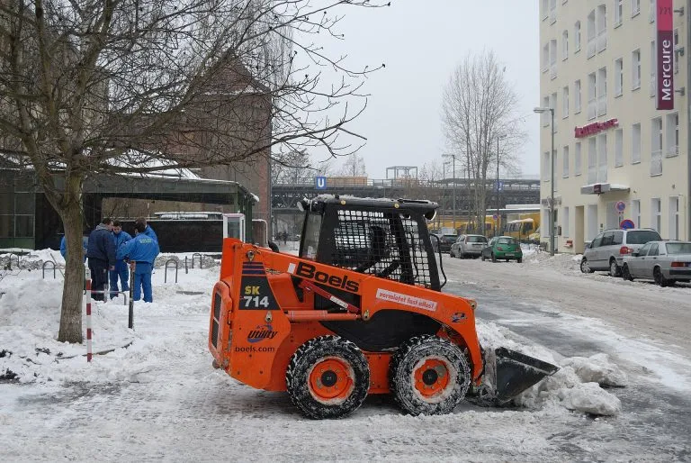 Skid-steer loader clearing snow on a city street